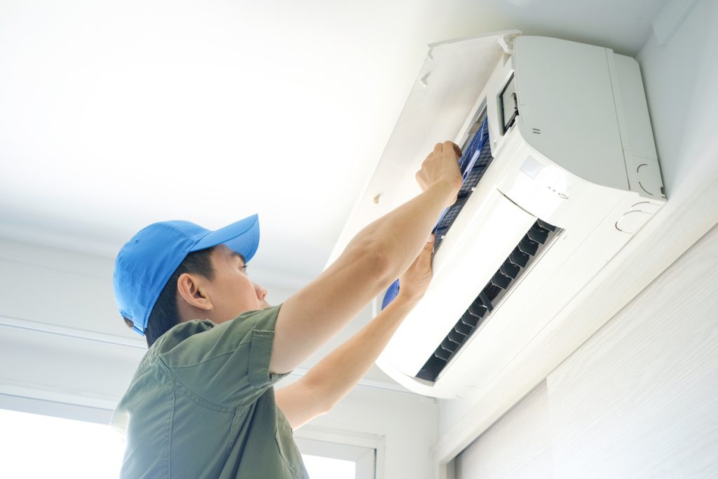 A male HVAC technician repairing an indoor air conditioner.